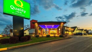 A Quality Inn by Choice Hotels building with a large illuminated sign, a well-lit entrance, and a parking area.