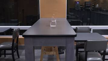 A modern dining area with a rectangular table, two chairs, a wooden stool, and a hanging pendant light.
