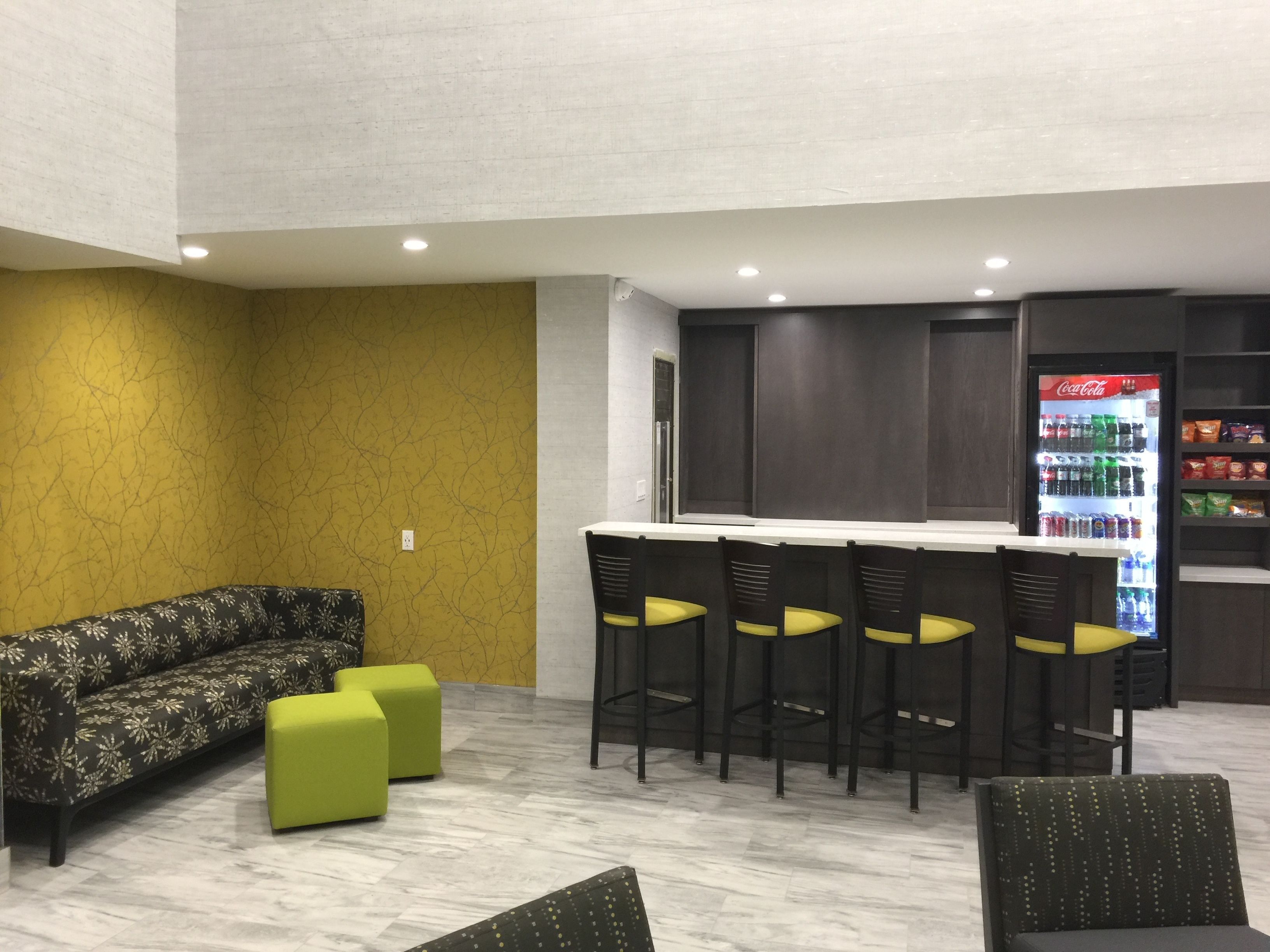 A bar area with a sofa, chairs, and a refrigerator stocked with beverages.