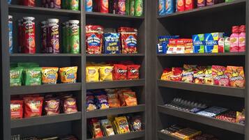 A snack and drink section with shelves stocked with various brands like Pringles, Planters, and TUMAX.