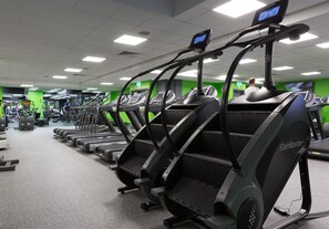 A row of treadmills in a gym with green walls and a tiled floor. - Village Hotel Manchester Cheadle (Cheadle)