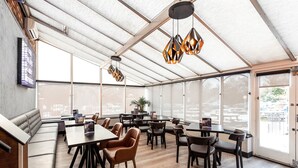 A spacious indoor area with a high ceiling, large windows, and modern lighting fixtures. - Village Hotel Manchester Cheadle (Cheadle)
