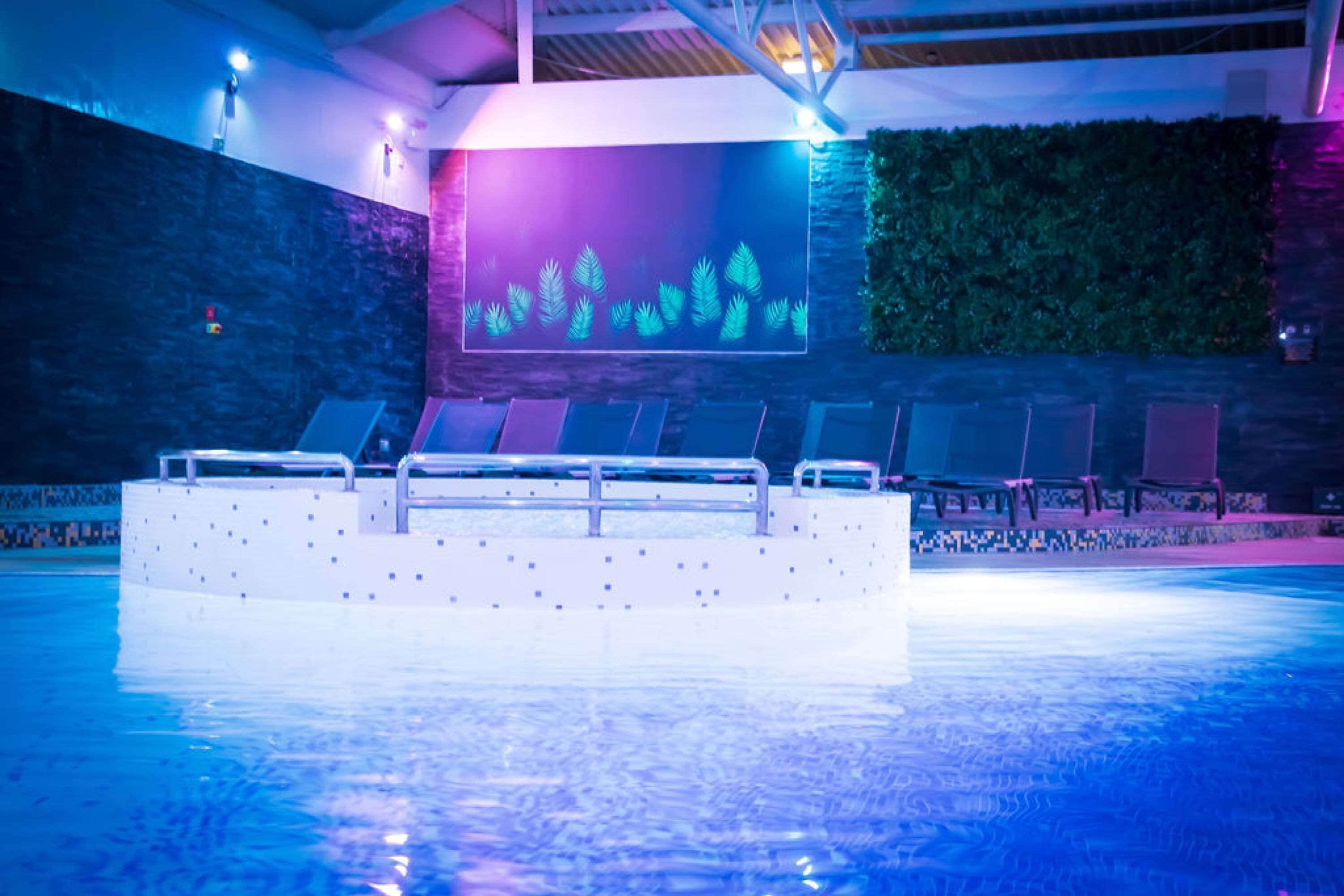 Een binnenzwembad, ligstoelen bij het zwembad