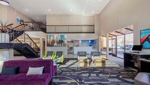 Eine großzügige Lobby mit Treppe, einer Sitzecke und einer Rezeption.