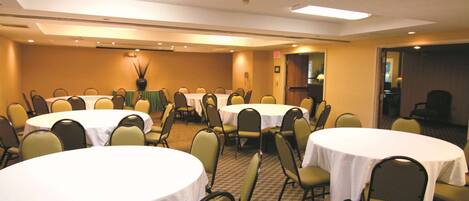 A conference room with multiple round tables and chairs, arranged in a U-shape.