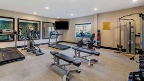 Ein Fitnessstudio mit Laufbändern, Crosstrainern, Bänken und Gewichten.