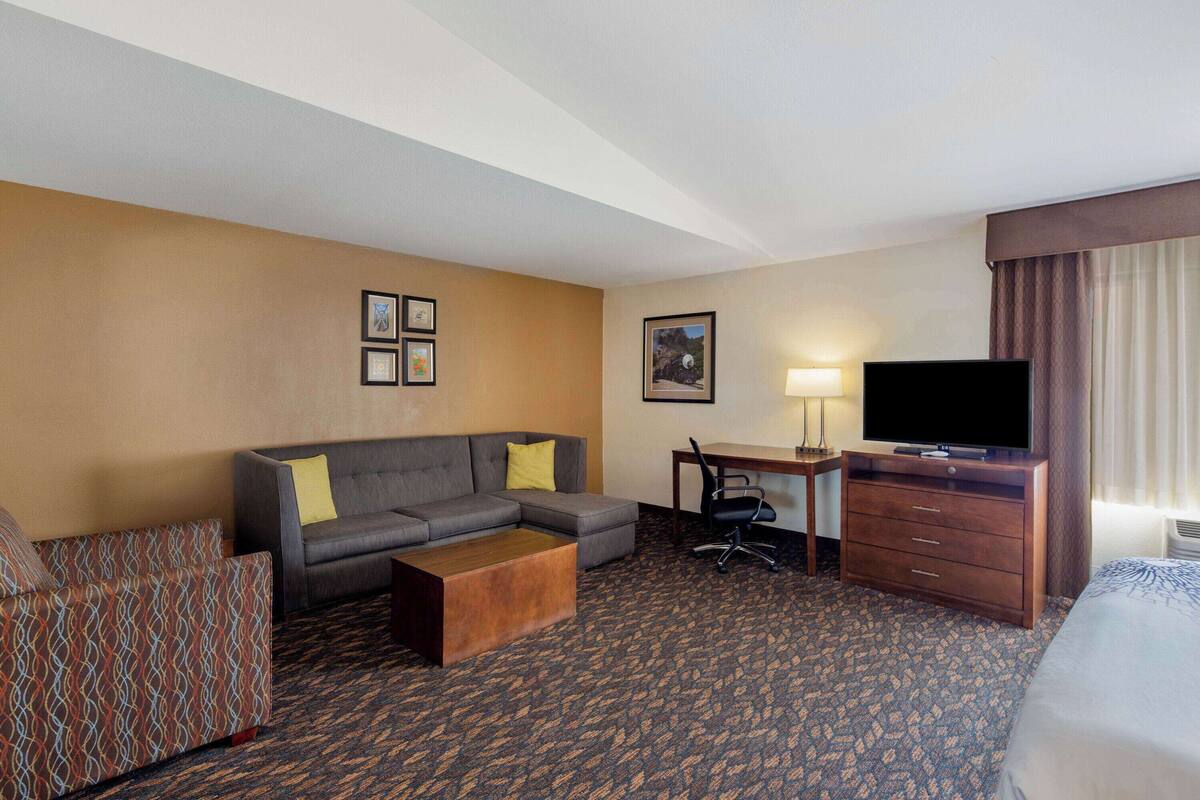Een hotelkamer met een bank, bureau, televisie en een bed.