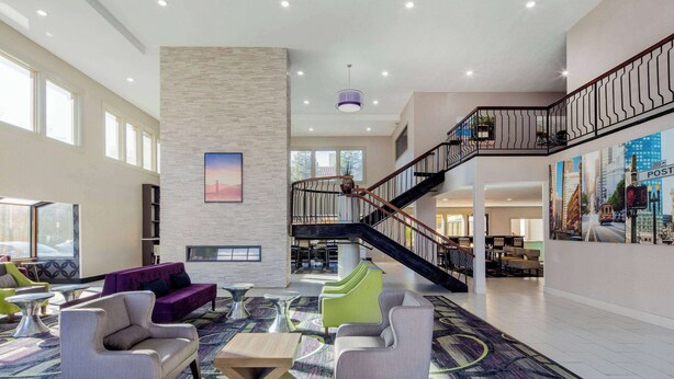 Eine großzügige Lobby mit hoher Decke, einer Treppe und einer Sitzecke mit moderner Möbel.