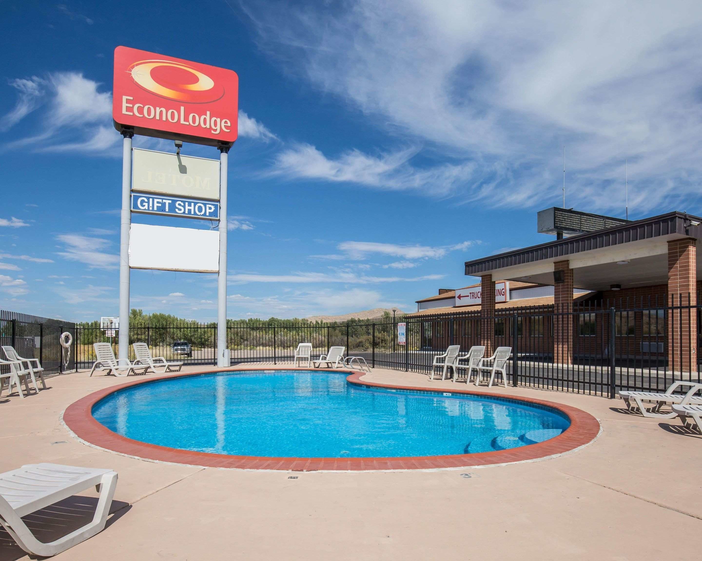 A pool area with lounge chairs, a sign for EconoLodge, and a gift shop.