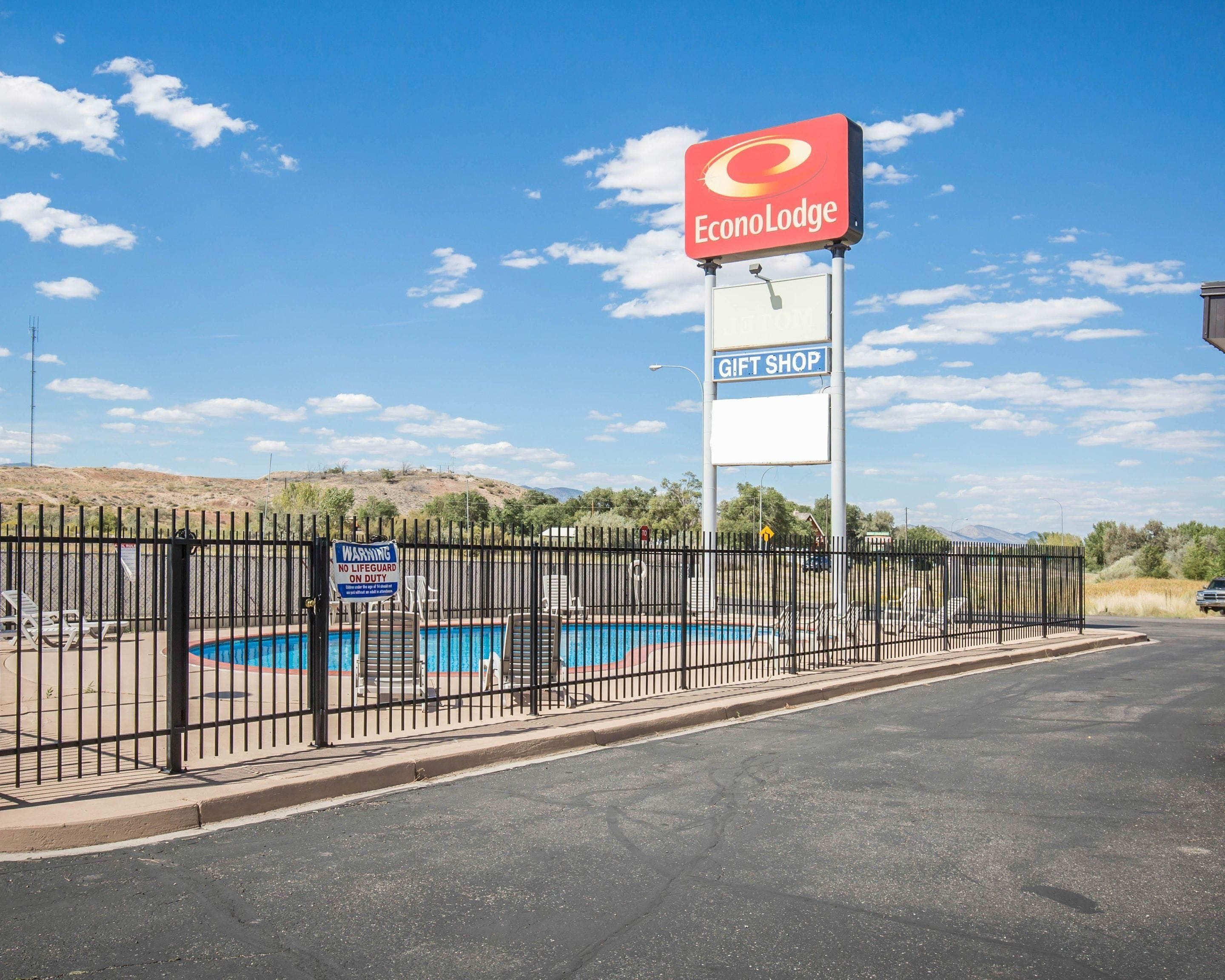 A fenced area with a swimming pool, a gift shop sign, and a warning sign.