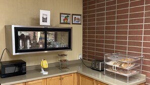 Un coin cuisine équipé d’un four à micro-ondes, d’un présentoir à fruits et d’un grille-pain.