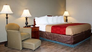 Une chambre d’hôtel avec un lit, deux lampes, une chaise et une table de chevet.