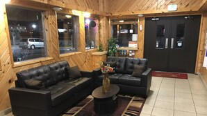 Un hall d’entrée avec deux canapés en cuir noir, une table basse et une plante en pot.