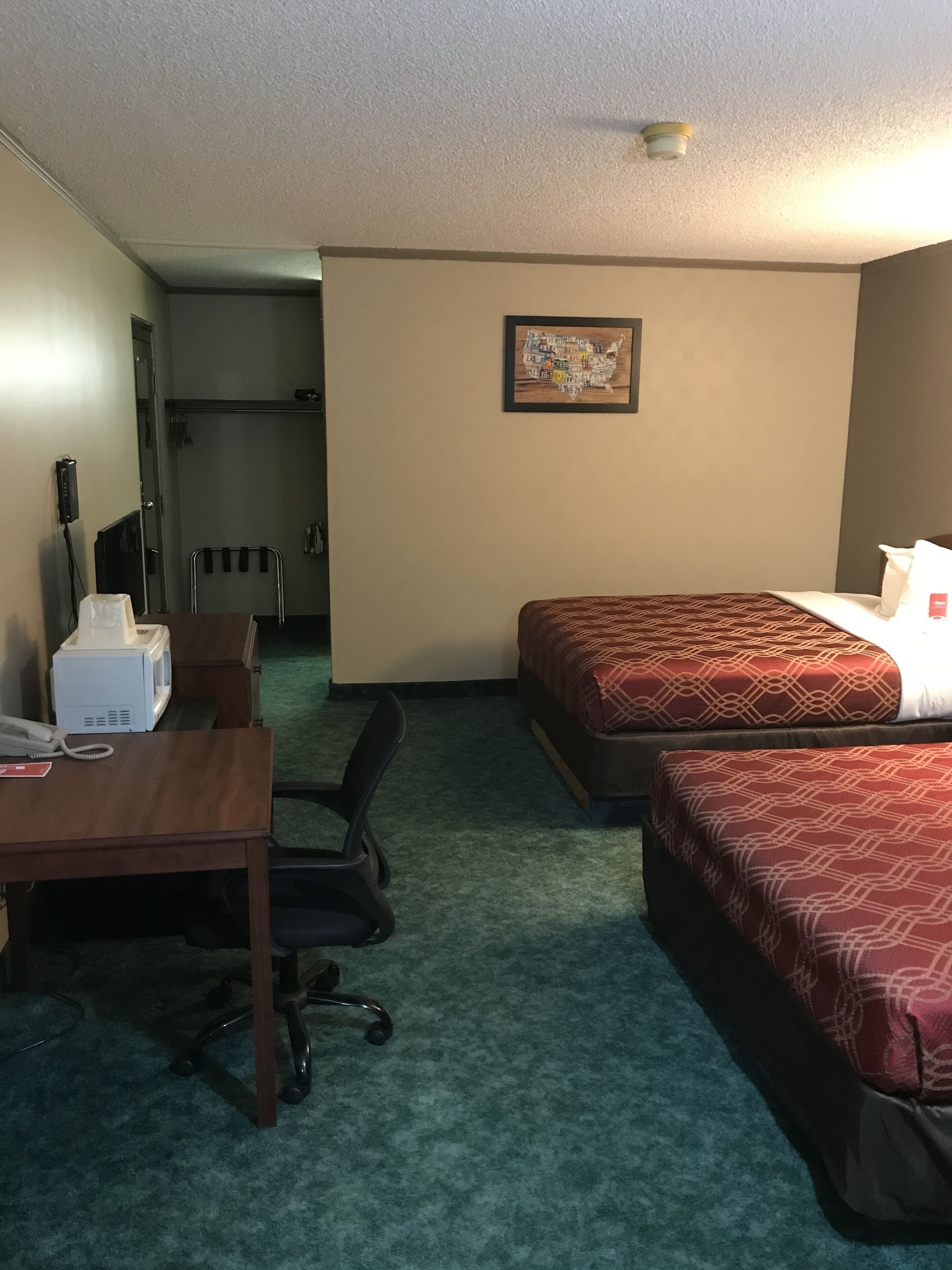 Een hotelkamer met twee bedden, een bureau, een stoel, een magnetron en een klein tafeltje.