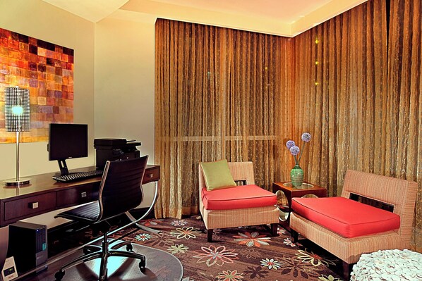 Una habitación de hotel con escritorio, computadora, silla, cama y cortinas.