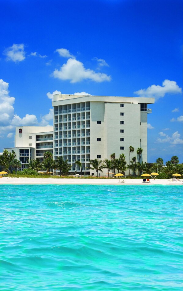 Un hotel moderno con un edificio grande, varios balcones y vista al mar.