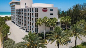 Een meerhoog hotel met een Marriott logo, omringd door palmbomen en een helder uitzicht op het strand.