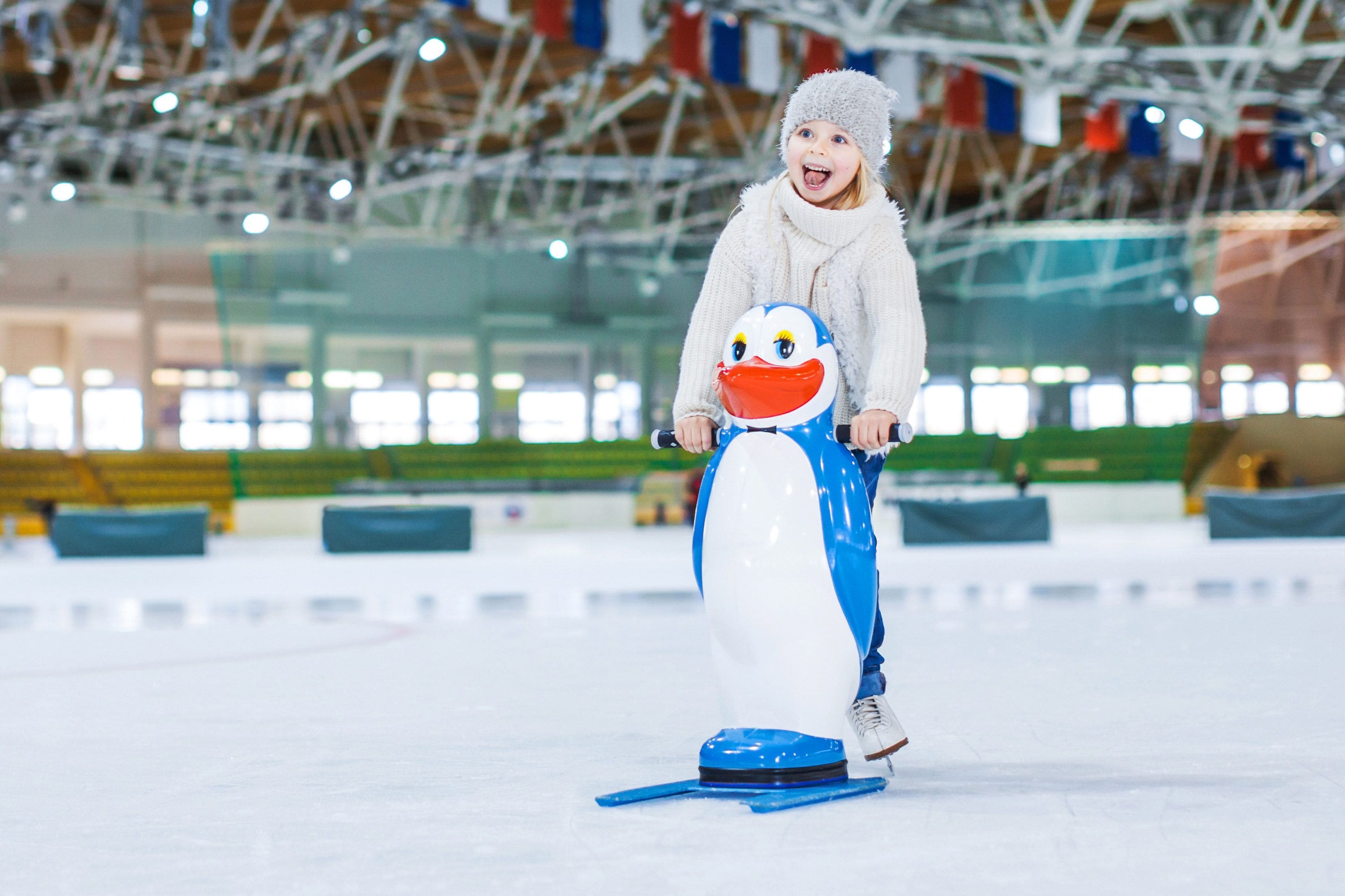 Un niño en una pista de hielo con un trineo con forma de pingüino.