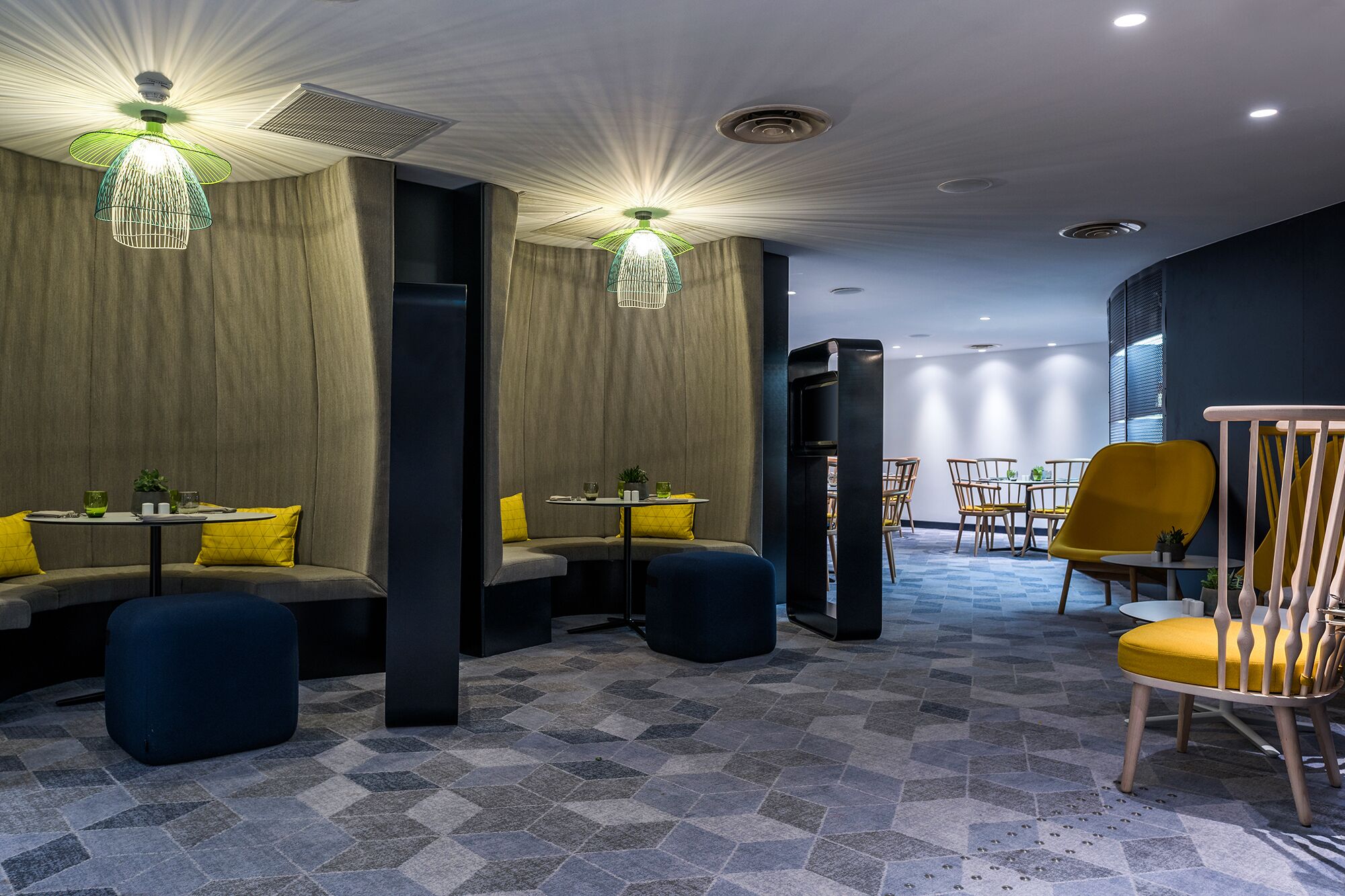 A modern interior with seating areas, tables, and a staircase leading to an upper level.