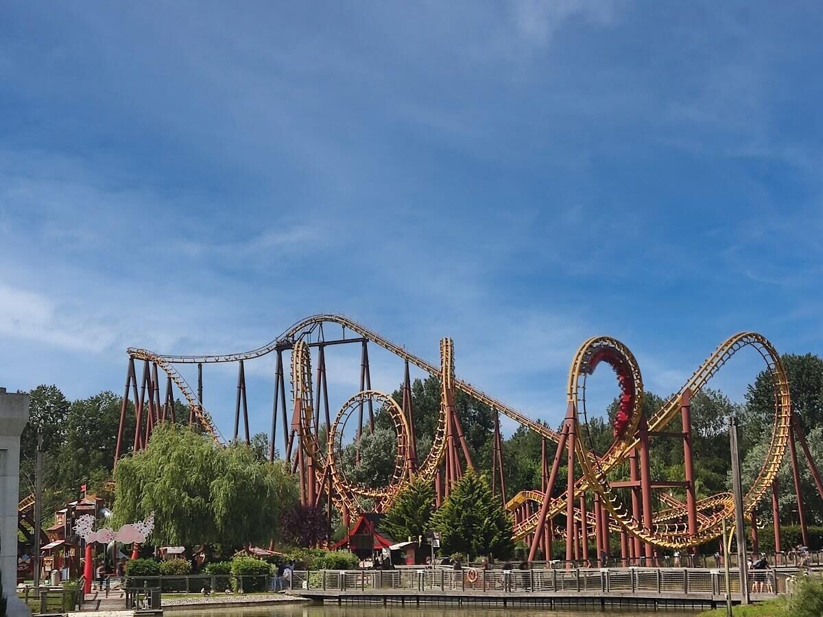 A roller coaster with multiple loops and a clear sky.