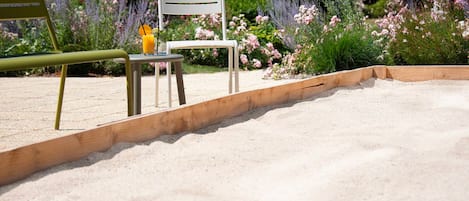 Un jardin avec un banc en bois, une chaise et une table avec des boissons.