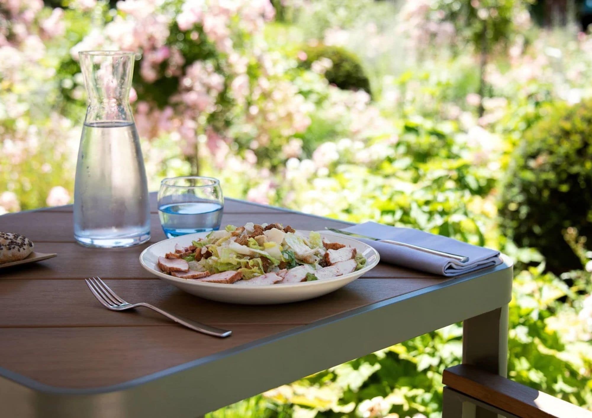 A table with a plate of food, a glass of water, a bottle of water, and a fork.