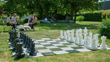 Play a game of chess in a serene park setting surrounded by trees.