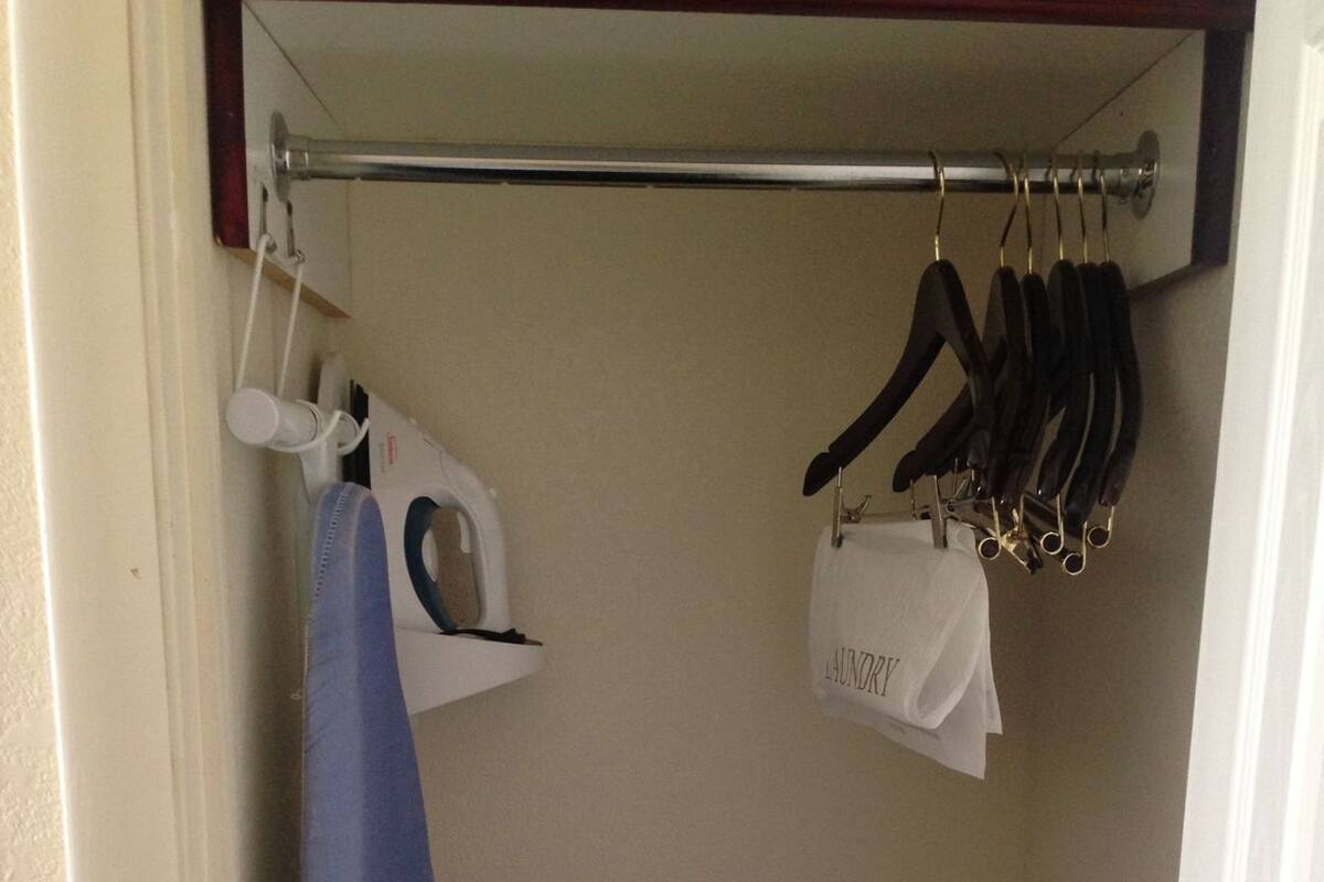 Une salle de bain avec une douche, un porte-serviettes avec une serviette bleue et un sac suspendu étiqueté « linge sale ».