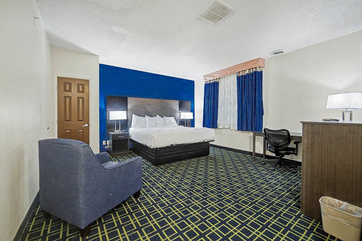 Une chambre d’hôtel équipée d’un lit, d’un bureau, d’une chaise et d’une poubelle.