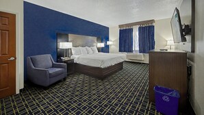 A hotel room with a bed, a chair, a desk, a TV, and a trash bin. - Baymont by Wyndham Greensburg (Greensburg)