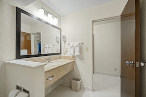 Une salle de bain avec un lavabo, un miroir, un porte-serviettes et une porte.