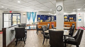 A restaurant with a counter, seating area, and exit signs. - Baymont by Wyndham Greensburg (Greensburg)