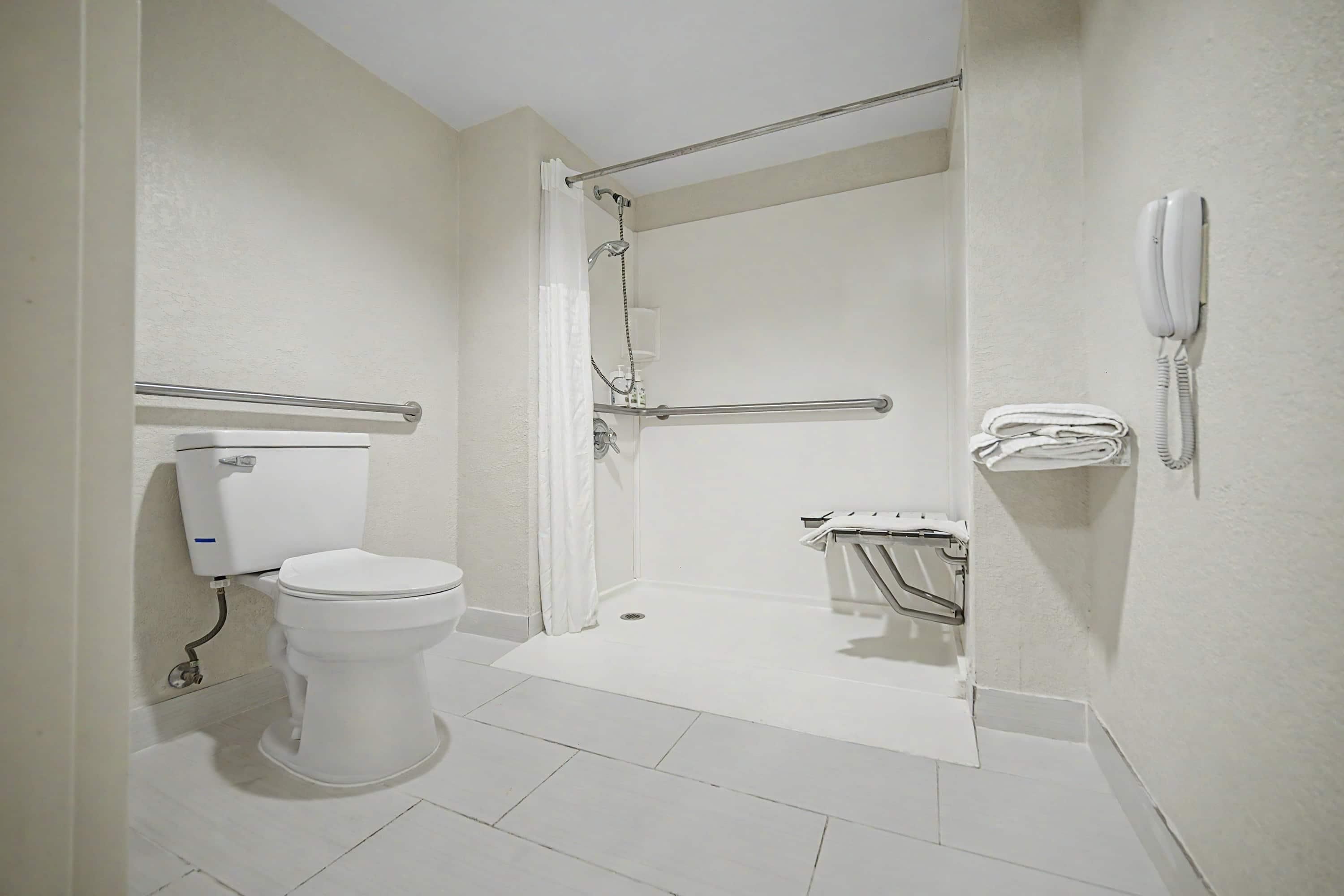 Une salle de bain équipée de toilettes, d’une douche et d’une barre d’appui.