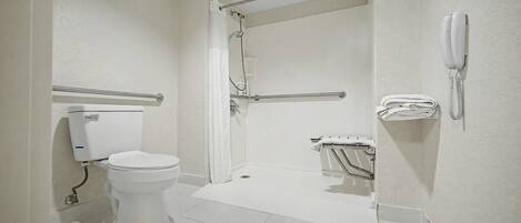 Un baño con inodoro, ducha y barra de apoyo.