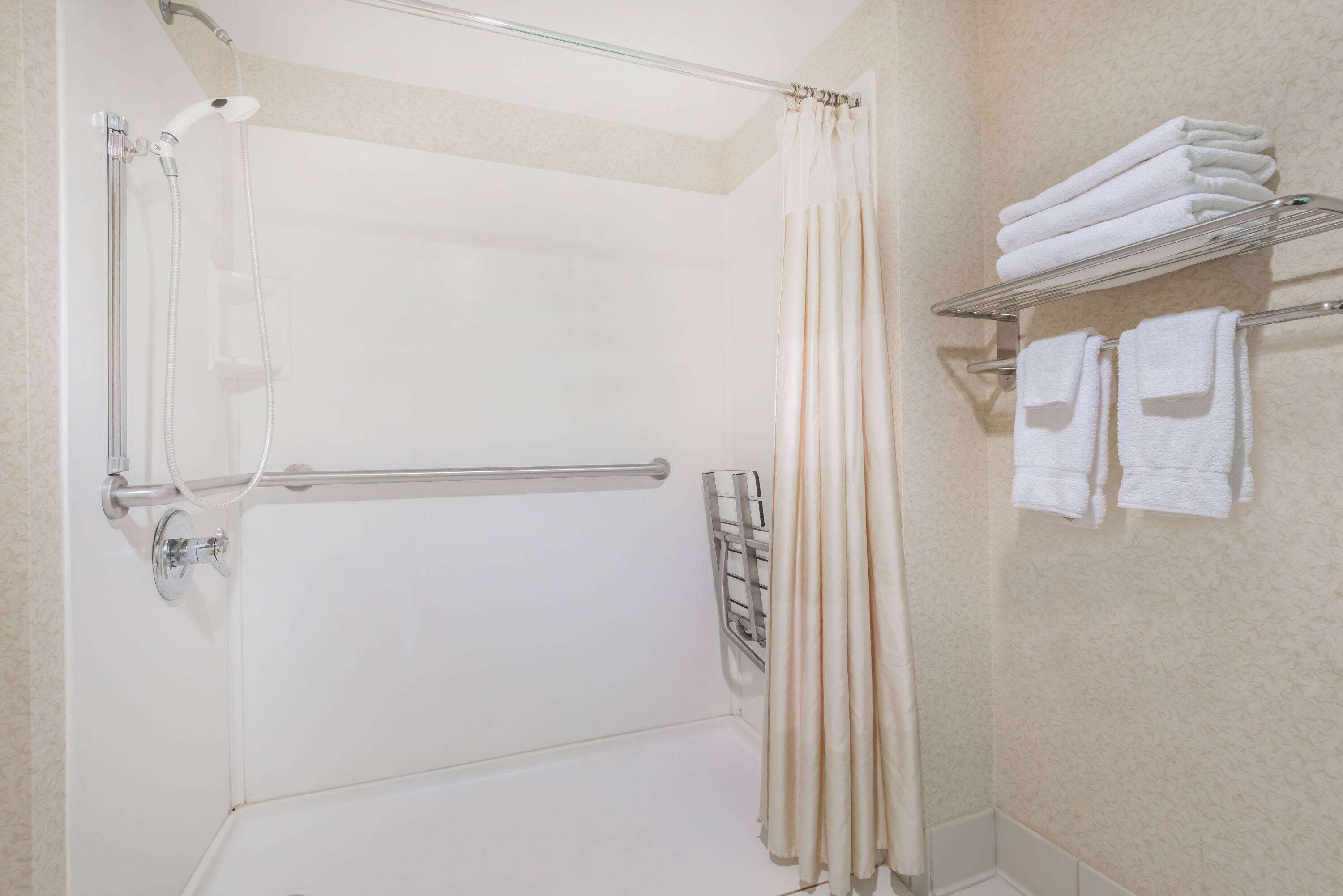 Un espace douche doté d’une porte en verre, d’un porte-serviettes avec des serviettes pliées et d’un panneau de commande de la douche.