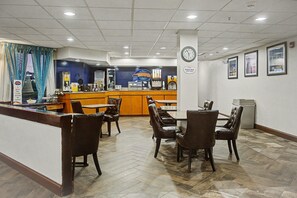 Eine Hotelhalle mit Empfangstheke, Sitzgelegenheiten und einer Wanduhr.