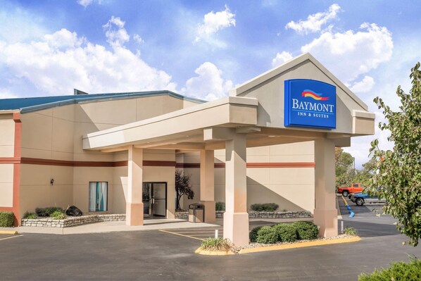 Un bâtiment de la chaîne Baymont Inn & Suites, avec un ciel dégagé, un parking et une enseigne.
