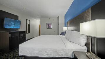 A hotel room with a bed, a TV, a desk, and a lamp.