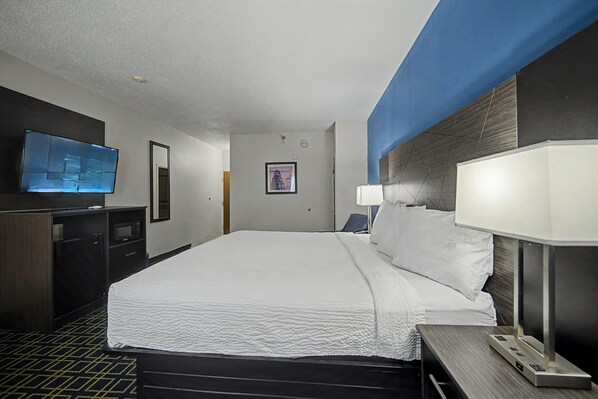 A hotel room with a bed, a TV, a desk, and a lamp.