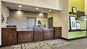 A reception area with a wooden reception desk, a 'hello' sign, and framed pictures on the wall. - Hampton Inn Norfolk-Naval Base (Norfolk)