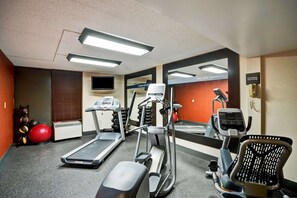 A gym with treadmills, elliptical machines, and exercise balls.