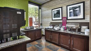 A kitchen area with a coffee machine, toaster, and food display.