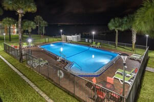 Una piscina rectangular con un borde de baldosas, rodeada por una valla metálica.