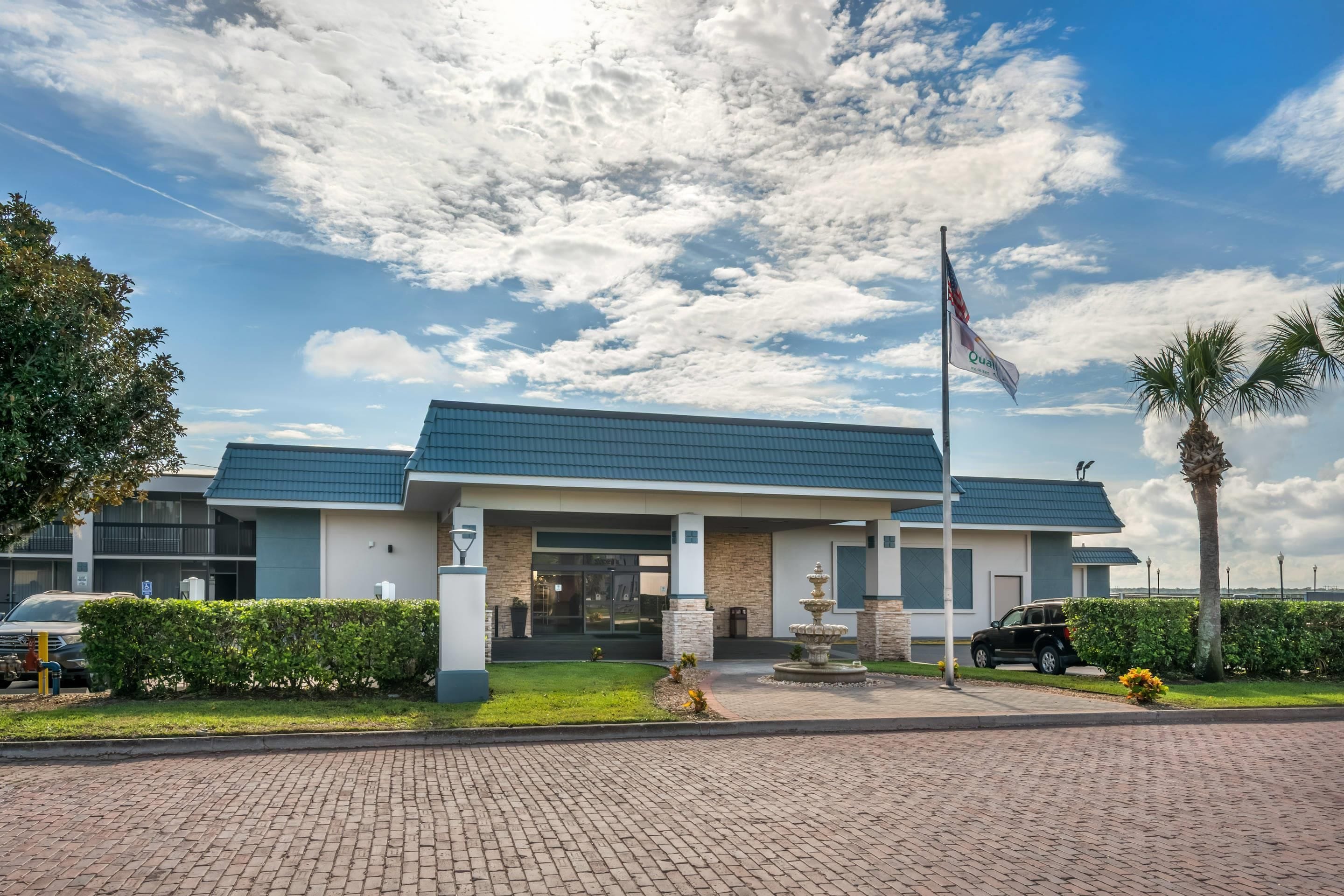 A modern building with a flat roof, a flagpole, and a landscaped entrance area.