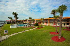 A motel with a swimming pool, palm trees, and a caution sign for manatees. - Quality Inn & Suites Palatka Riverfront (Palatka)