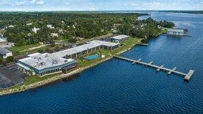 An aerial view of a waterfront property with a dock extending into a body of water, surrounded by greenery and residential buildings. - Quality Inn & Suites Palatka Riverfront (Palatka)