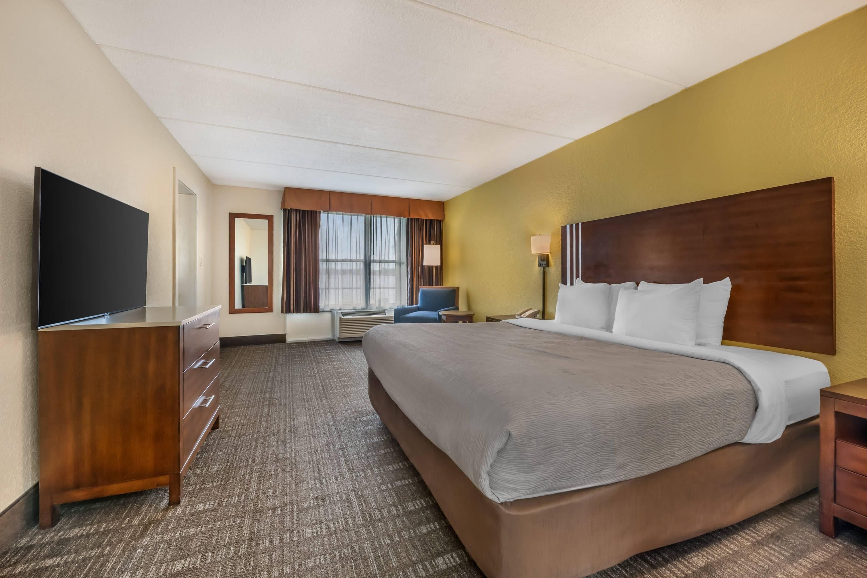 A hotel room with a large bed, a flat-screen TV, a desk, and a chair.