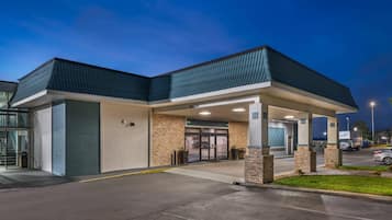 A modern building with a covered entrance, a clear sign, and a parking area.