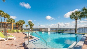 A swimming pool with a tiled edge, surrounded by lounge chairs and palm trees. - Quality Inn & Suites Palatka Riverfront (Palatka)