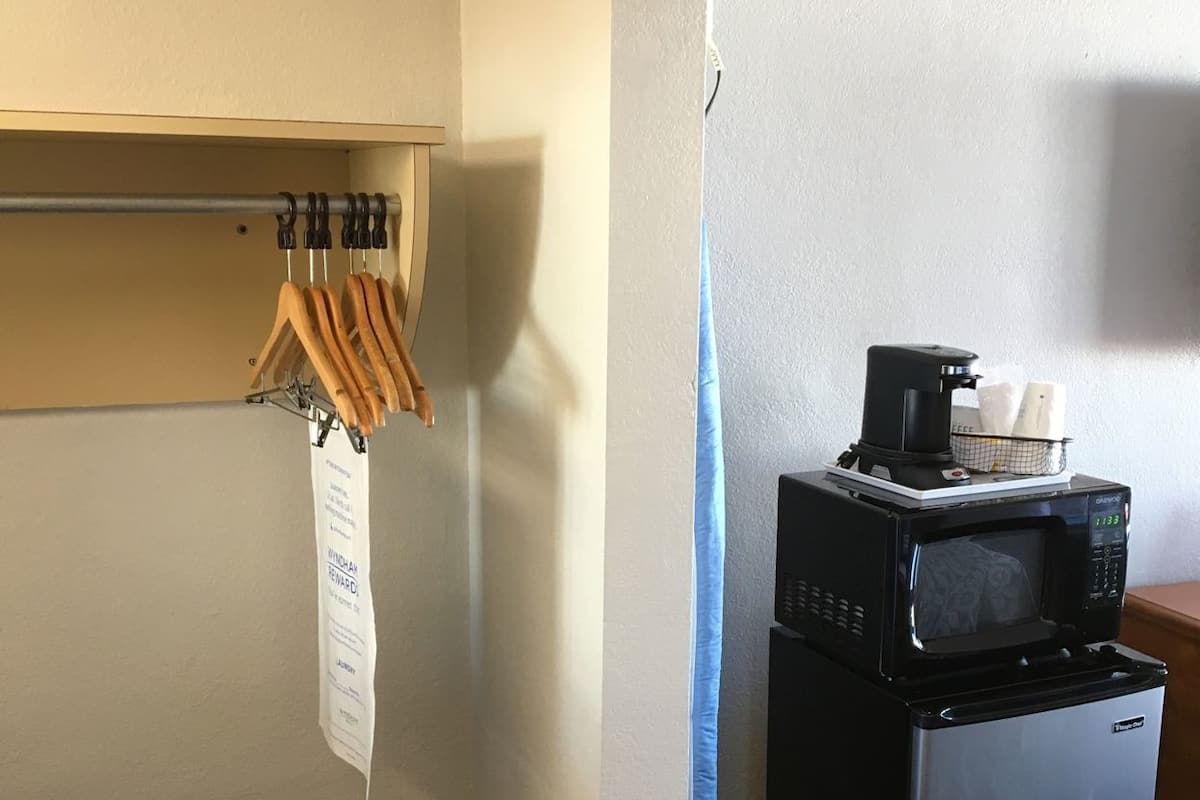 Habitación de hotel con kitchenette, microondas, refrigerador, cafetera y perchero.